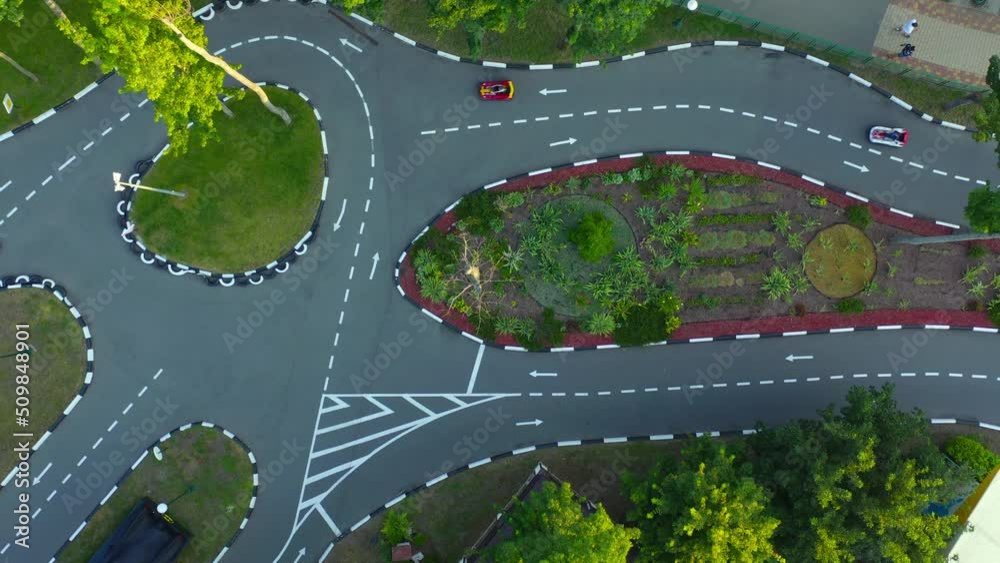 Karting Motion on asphalt road with white markings. Karting Attraction Track: People ride small cars on an asphalt race track: aerial top down drone shot.