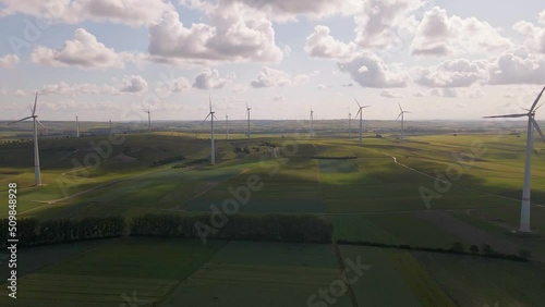 A remote wind park underneath a bright  sunny sky dominated by cumulus clouds in west Germany. Wide angle aerial pull back shot photo