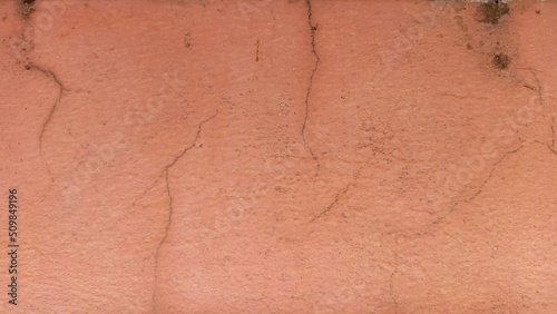 Cracks on the old orange wall and peeling paint.