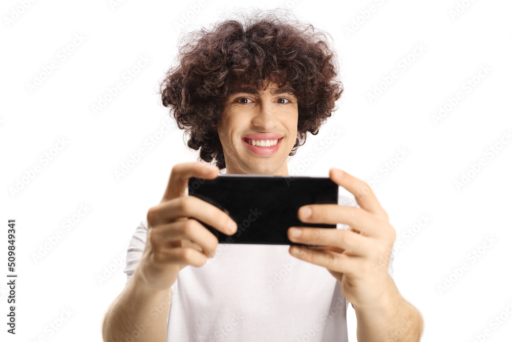 Casual young man with a curly hair taking a photo with a smartphone Casual young man with a curly hair taking a photo with a smartphone