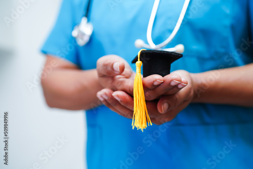 Asian woman doctor holding graduation hat in hospital, Medical education concept. photo