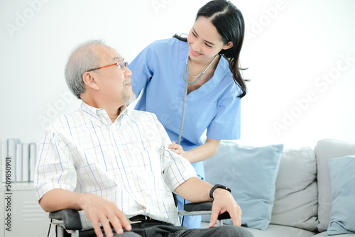 Young female doctor helping to take care of grandfather sitting in wheelchair.