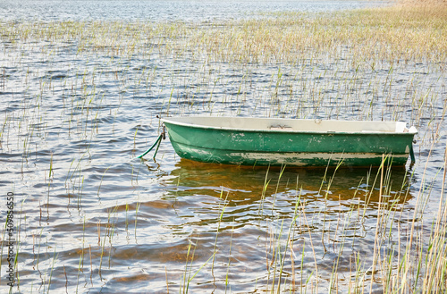 Small green boat anchored in forest lake. Scandinavia. Transportation, traditional craft, recreation, leisure activity, healthy lifestyle, local tourism, sport, rowing, hiking, summer vacations themes photo