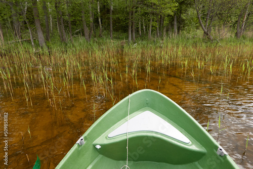 Small green boat anchored in forest lake. Scandinavia. Transportation, traditional craft, recreation, leisure activity, healthy lifestyle, local tourism, sport, rowing, hiking, summer vacations themes photo