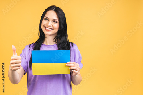 Portrait of nice beautiful lovely glad cheerful woman holding in hands Ukrainian flag having fun isolated over yellow pastel color background.