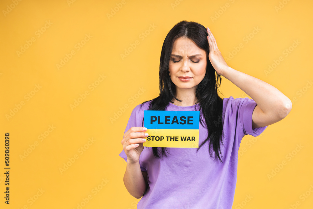 Stop war in Ukraine! Portrait of sad agressive angry woman holding in hands Ukrainian flag isolated over yellow pastel color background. Stop war in Ukraine! Portrait of sad agressive angry woman holding in hands Ukrainian flag isolated over yellow pastel color background.