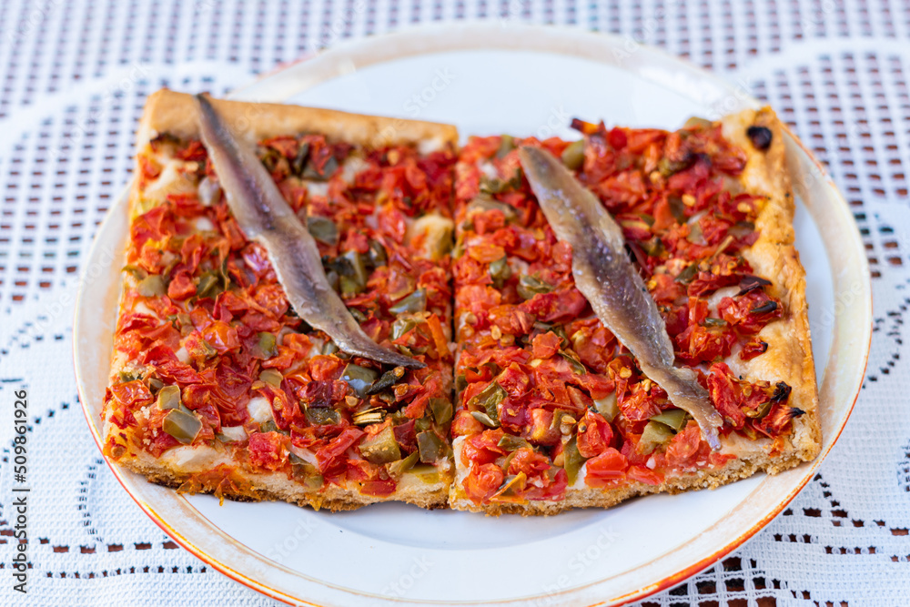 Tomato and vegetable pizza with anchovies, on a white plate, on a crochet tablecloth Tomato and vegetable pizza with anchovies, on a white plate, on a crochet tablecloth