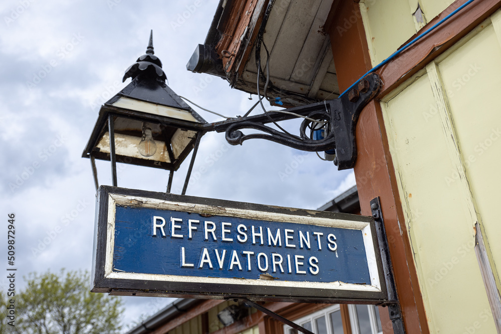 Obraz premium Old weathered blue wooden sign saying Refreshments lavatories sign at Bolton Abbey railway station, Yorkshire, UK