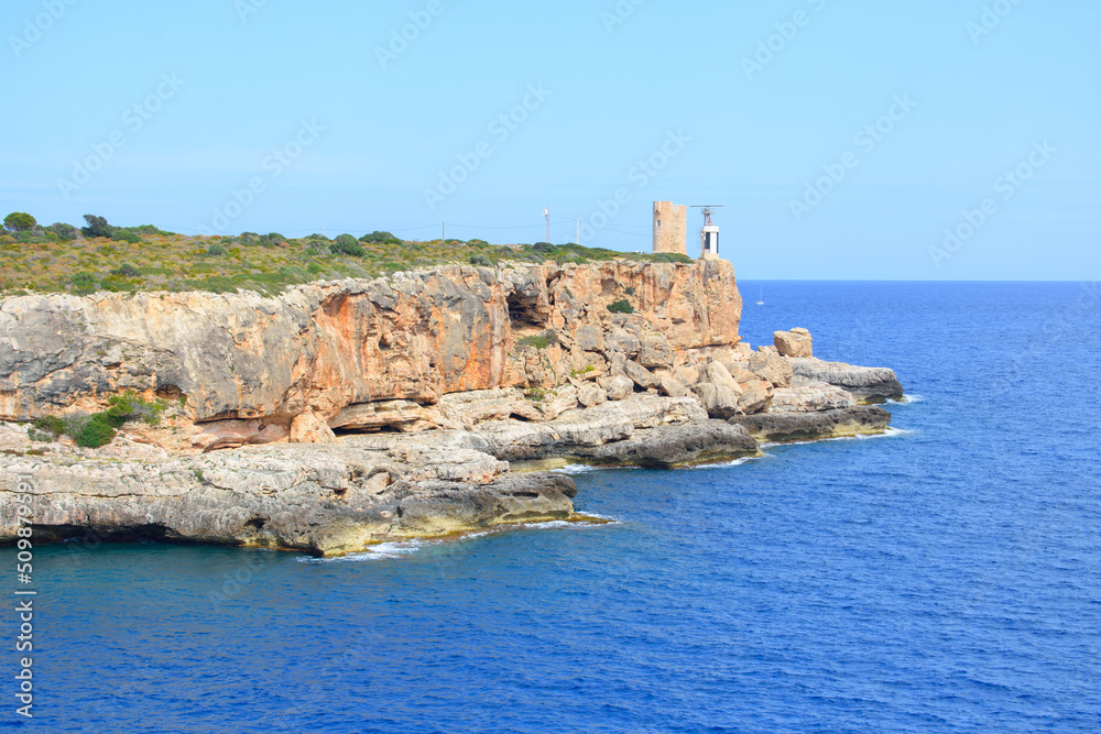 Watchtower Torre d'en Beu in Cala Figuera, Mallorca, Spain. Blue sea water and red cliffs.