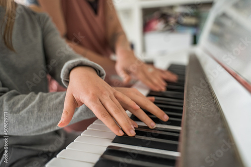 Caucasian mother teaching her child girl to play piano