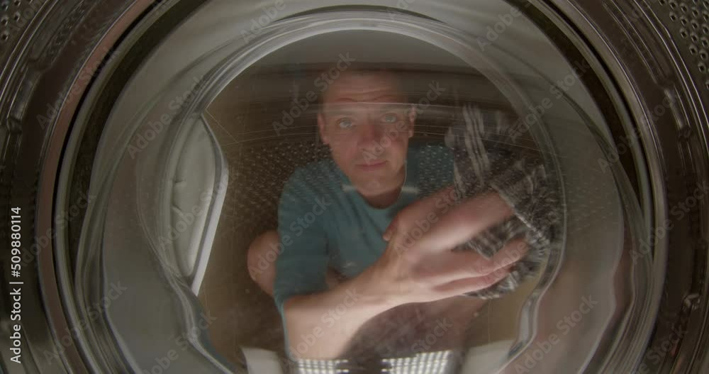 The cleaning worker cleans the glass of the washing machine. He wipes the lid with a rag, carefully removes stains and dirt. Maintenance of household appliances. The cleaning worker cleans the glass of the washing machine. He wipes the lid with a rag, carefully removes stains and dirt. Maintenance of household appliances.