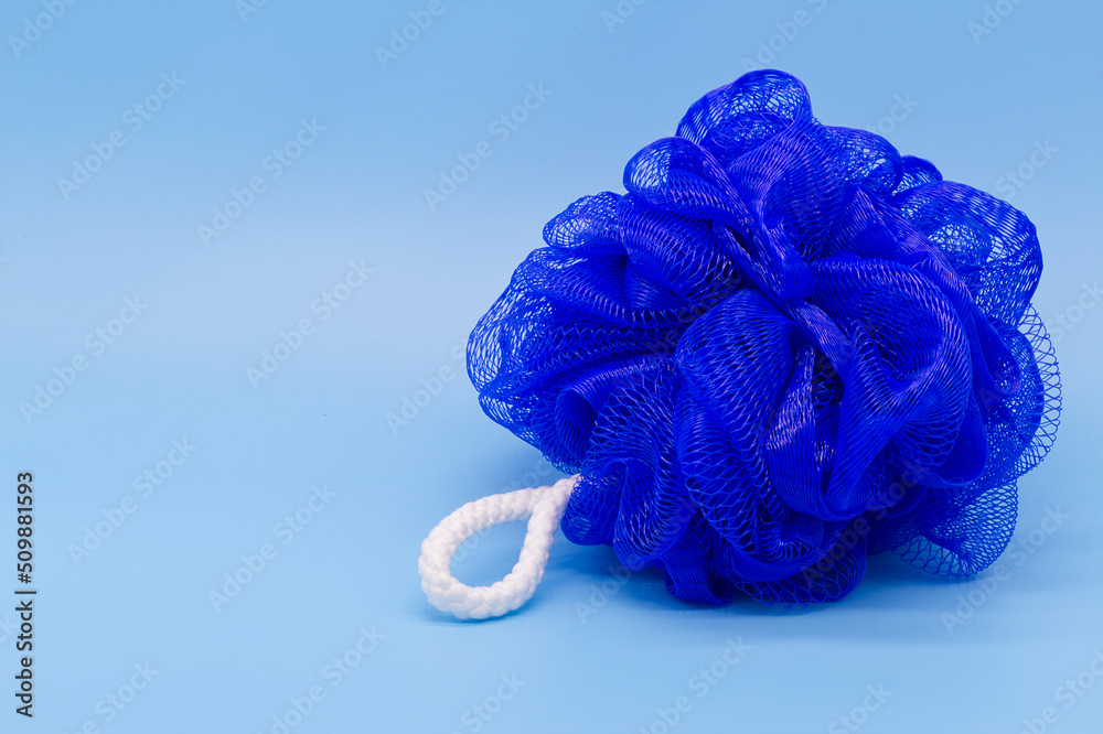 Blue mesh pouf bath sponge washcloth single object on blue background  closeup photo with copy space. Soft synthetic shower wash cloth. Washing  hygiene design element. Spa body care accessory product. Photos