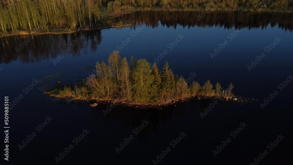 Bank of a wide navigable river illuminated by the setting sun. The forest is reflected in the calm river water. Bank of a wide navigable river illuminated by the setting sun. The forest is reflected in the calm river water.