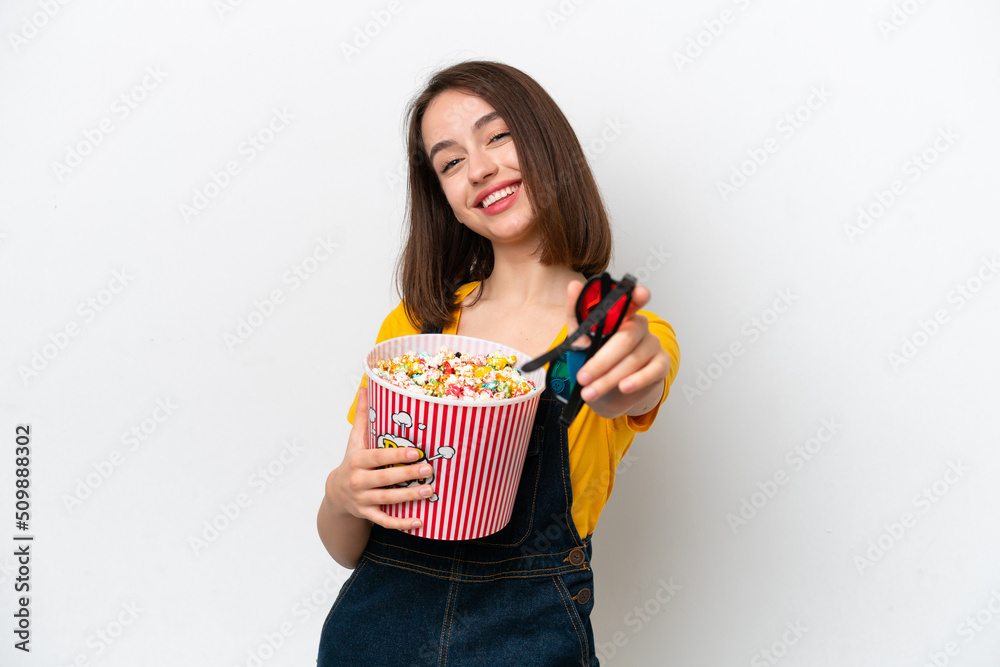 Young Ukrainian woman isolated on white background with 3d glasses and holding a big bucket of popcorns