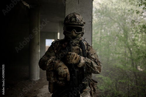 Fotografiet Military soldier in uniform standing with a weapon in his hands at night