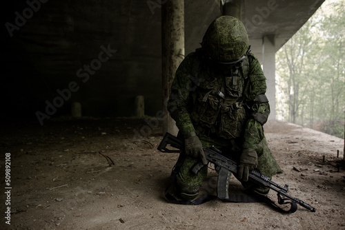 Fotografia Military soldier in uniform sitting on his knees with his head down