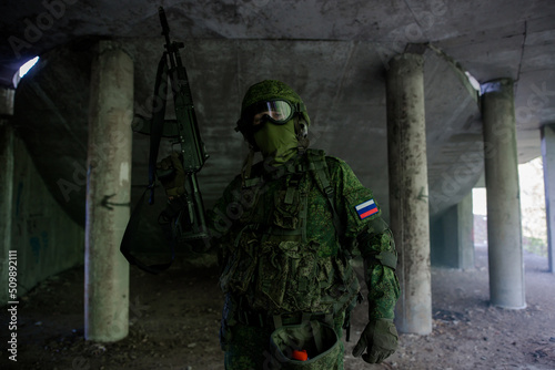 Russian military soldier in uniform holding up his weapon