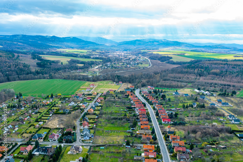Village landscape from above, aerial view of private rural houses among green fields and mountains