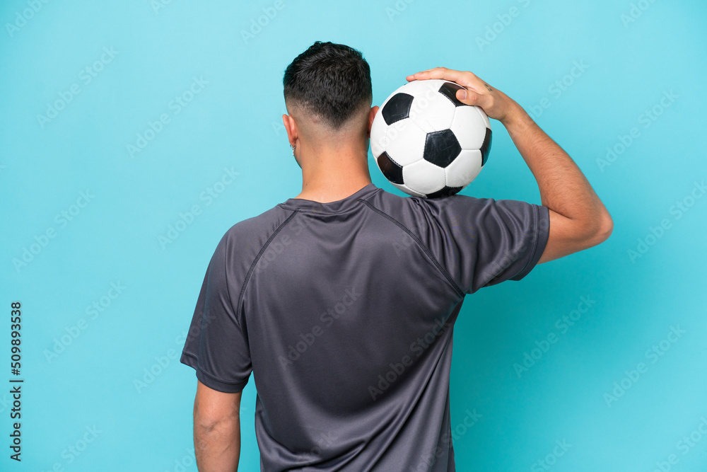 Young Arab handsome man isolated on blue background with soccer ball