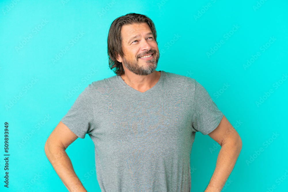Senior dutch man isolated on blue background posing with arms at hip and smiling Senior dutch man isolated on blue background posing with arms at hip and smiling