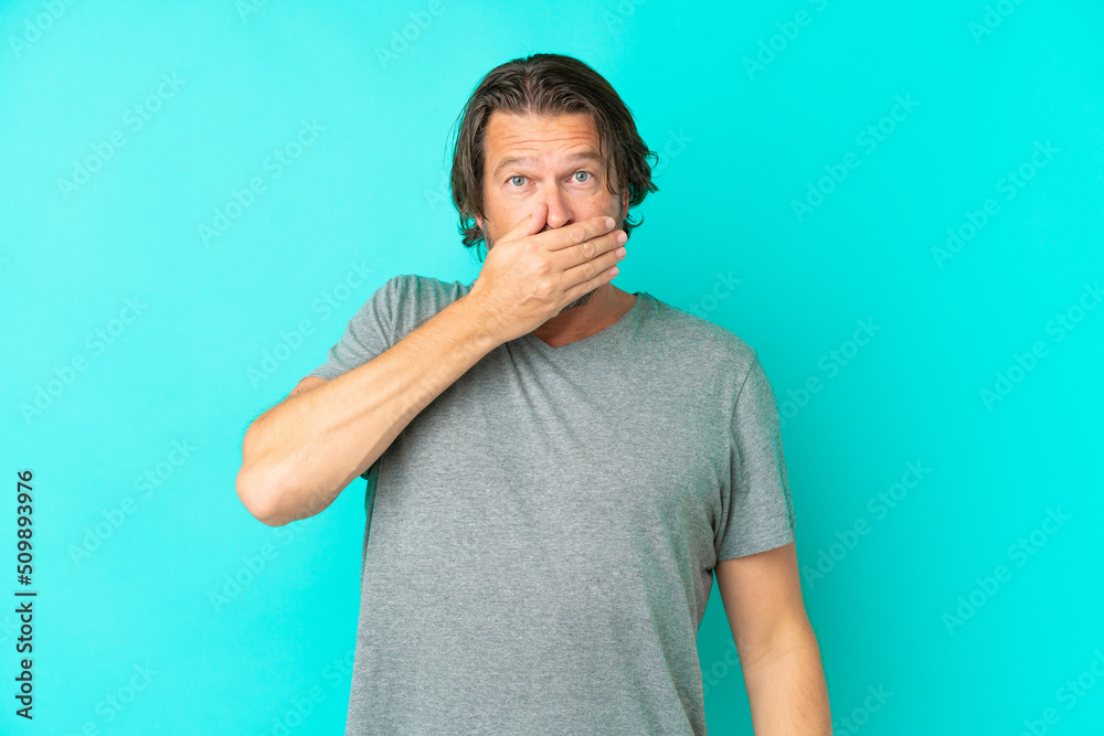 Senior dutch man isolated on blue background covering mouth with hand Senior dutch man isolated on blue background covering mouth with hand