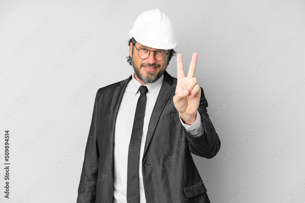 Young architect man with helmet over isolated background smiling and showing victory sign Young architect man with helmet over isolated background smiling and showing victory sign