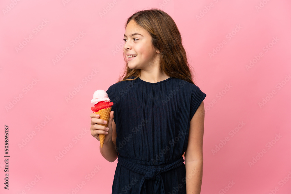 Child with a cornet ice cream over isolated pink background looking side Child with a cornet ice cream over isolated pink background looking side