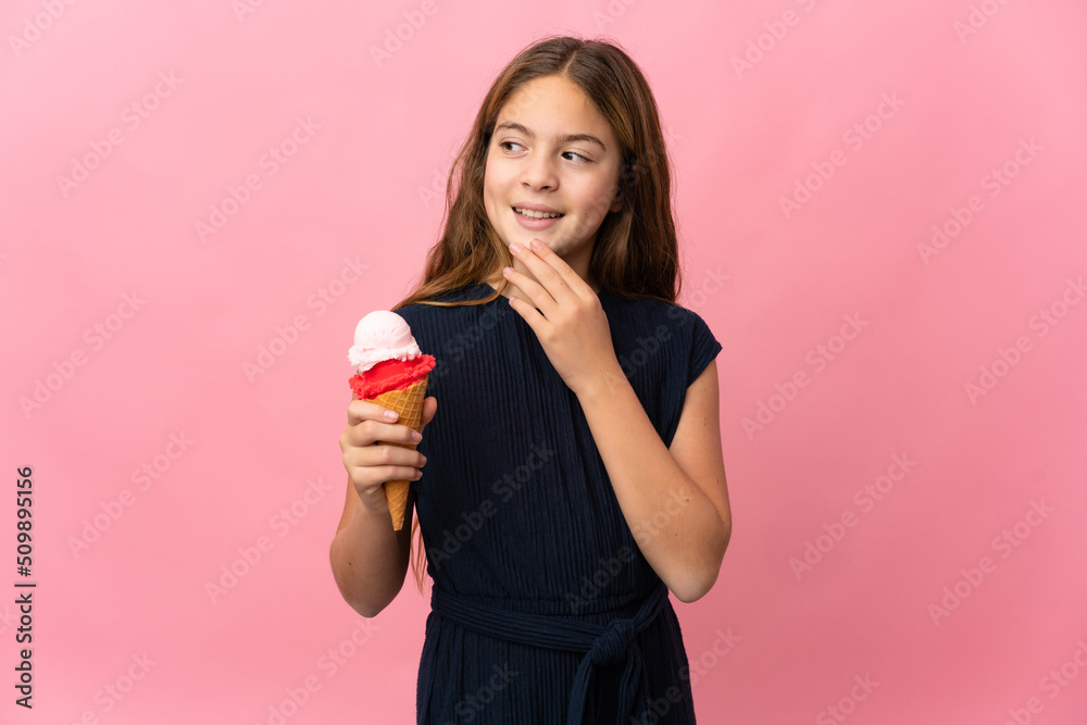 Child with a cornet ice cream over isolated pink background looking up while smiling Child with a cornet ice cream over isolated pink background looking up while smiling