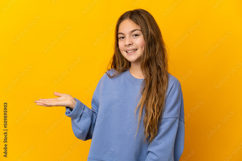 Child over isolated yellow background presenting an idea while looking smiling towards Child over isolated yellow background presenting an idea while looking smiling towards