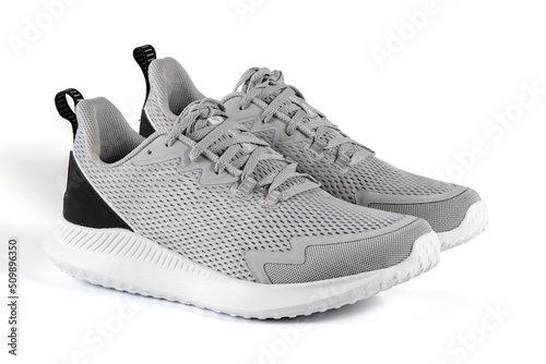 New unbranded running sneaker or trainer isolated on white background. Men's light grai sport footwear. Close-up of a pair sneakers or sport shoes.