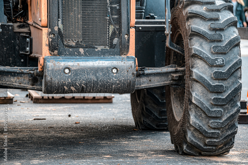 Part of the tractor shows the suspension and shock absorber system, as well as the large front tire from bottom to top.
