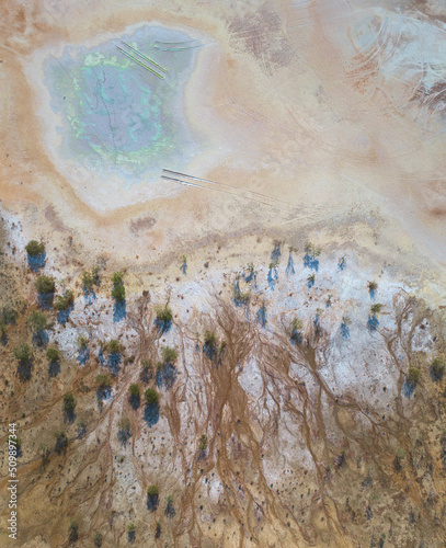 Abandoned open pit copper mine with colorful spots of chemicals. Toxic mine dumps surface, aerial view directly above