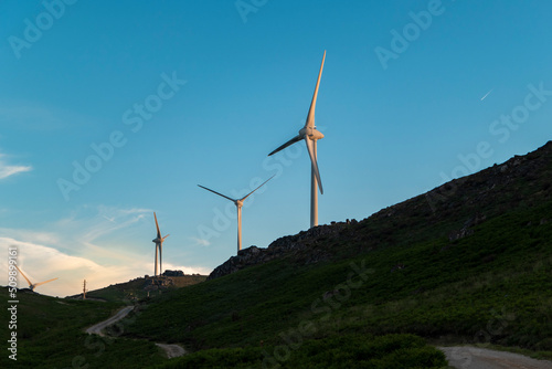 Turbinas eólicas na paisagem montanhosa ao pôr do sol com uma estrada sobre a montanha photo