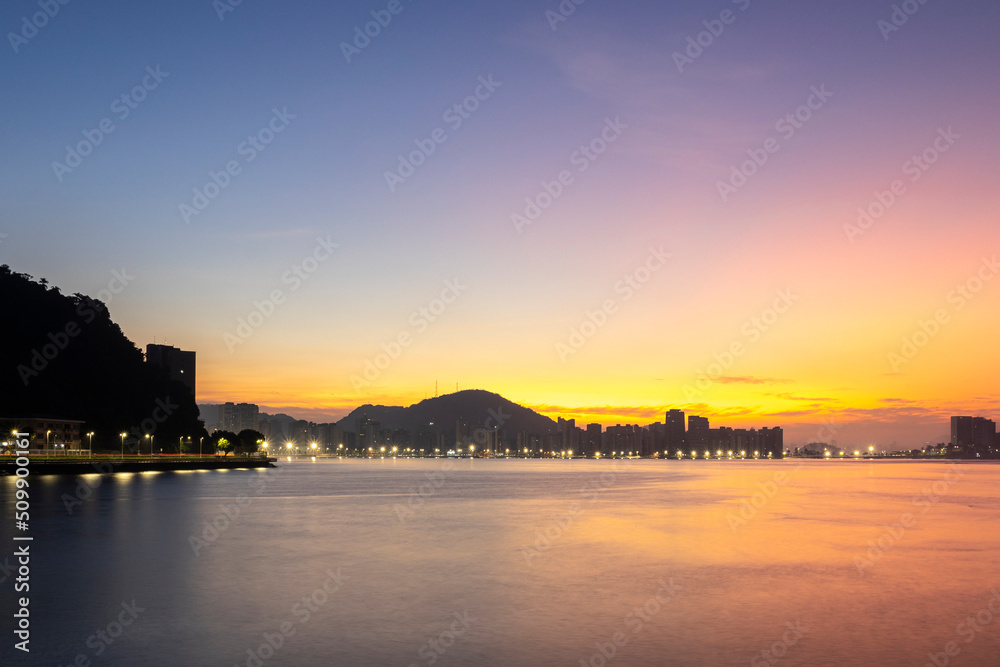Sunrise on the sea with the silhouette of the mountains in the city