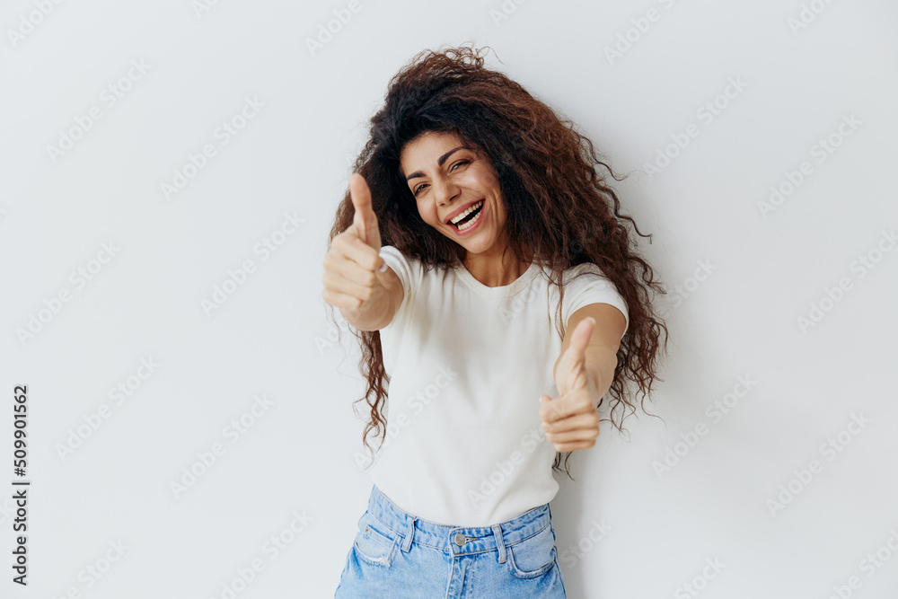 IT'S SUPER CONCEPT. Overjoyed stylish curly Latin female look at camera, smile show thumbs gesture, say Great idea. Copy space for fashion brand, free place ad. Studio shoot isolated white background IT'S SUPER CONCEPT. Overjoyed stylish curly Latin female look at camera, smile show thumbs gesture, say Great idea. Copy space for fashion brand, free place ad. Studio shoot isolated white background