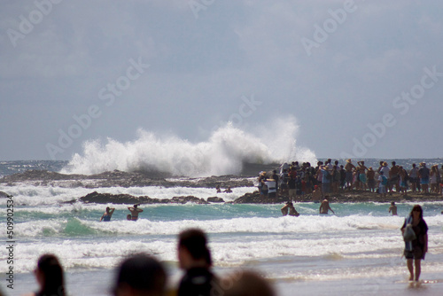 Huge Surf Smashing Rocks with People in the Water photo