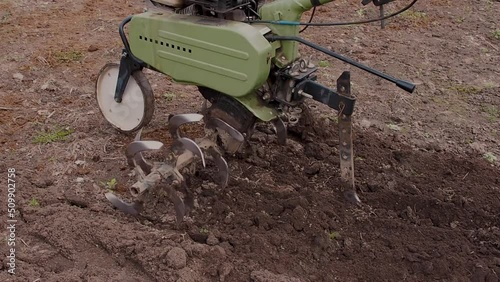 Wallpaper Mural motor cultivator or tiller tractor cultivates the ground soil in the garden close up. Modern plowing farming and technology agriculture. Torontodigital.ca