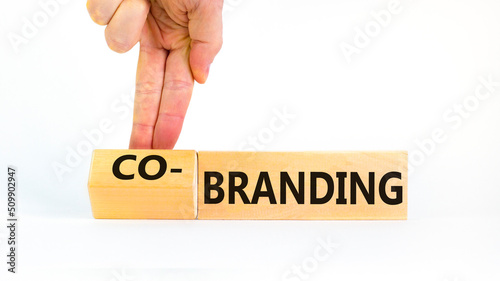 Branding or co-branding symbol. Businessman turns wooden cubes and changes the word Branding to Co-branding. Beautiful white table white background, copy space. Business branding co-branding concept. photo