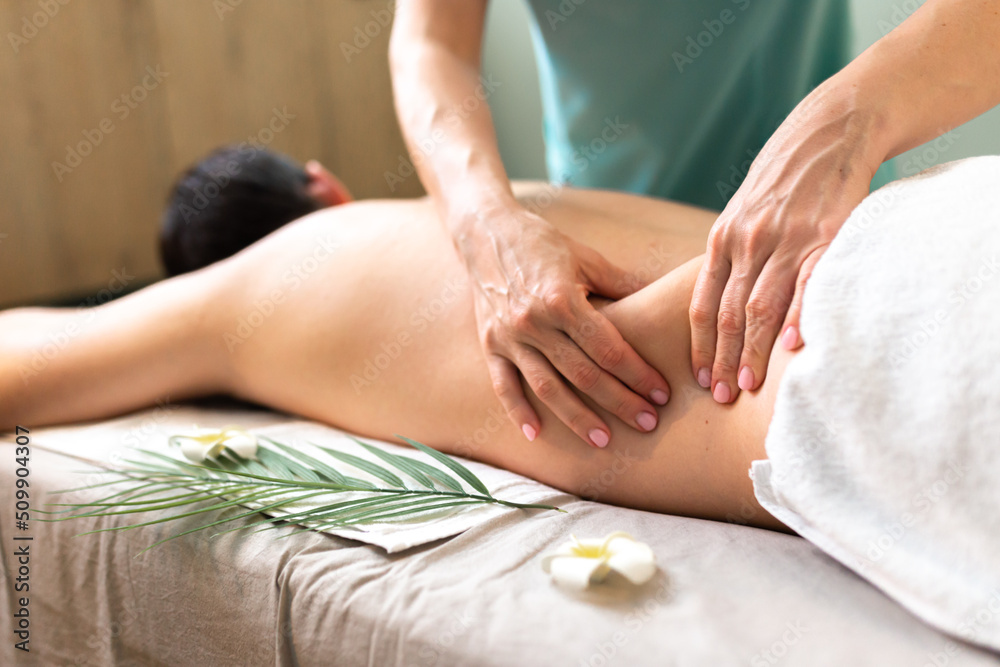 Man receiving back massage from masseur in spa Man receiving back massage from masseur in spa