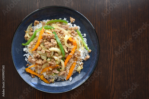 Stir fried minced pork with bell pepper, garlic and onion topped on rice on a plate. Flat lay top view photo. Food from above. 