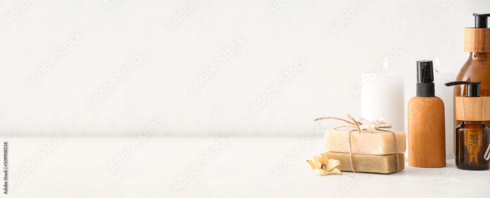 Naklejka premium Soap with cosmetics and aroma candle on light background with space for text