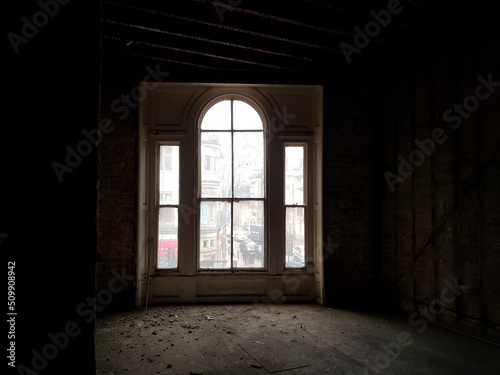 A large window in an old, abandoned and dark house.