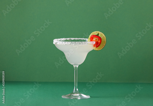 Glass of tasty margarita cocktail on color background photo