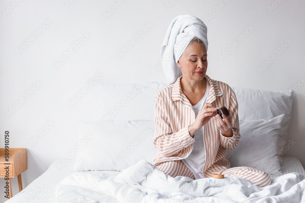 Morning of mature woman applying cream in bedroom Morning of mature woman applying cream in bedroom