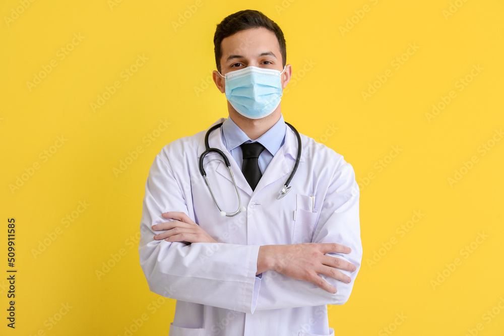 Male doctor in medical mask on yellow background Male doctor in medical mask on yellow background