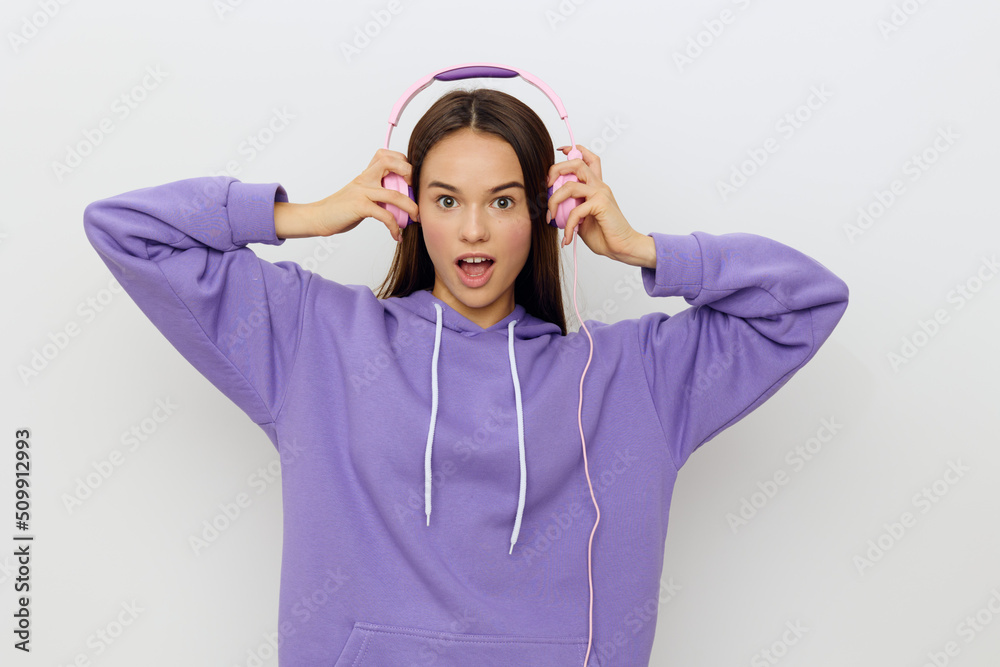 a sweet, beautiful, pleasant woman stands in purple clothes on a white background and puts on headphones a sweet, beautiful, pleasant woman stands in purple clothes on a white background and puts on headphones