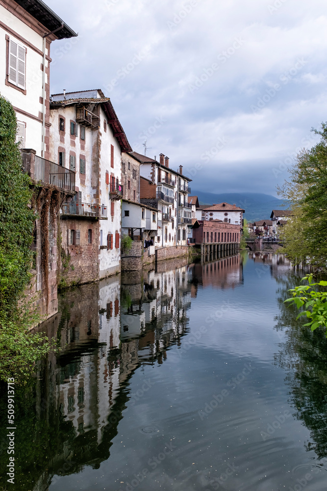 Old houses on the edge of a channel on the Bidasoa river with the buildings reflecting on the water, in the picturesque village of Elizondo, traditional Basque houses, Batzan valley, Navarra, Spain,