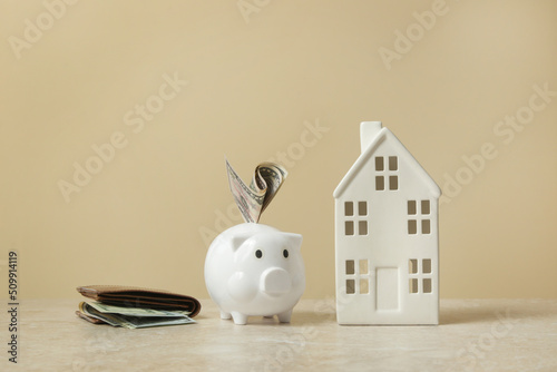 Home budget planning. Cost of living. Inflation concept. Concept of saving money for buying new house. Piggy bank, wallet with dollar banknotes and model of house.  photo