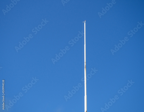 Empty white flagpole against the blue sky. Lowered flag. photo