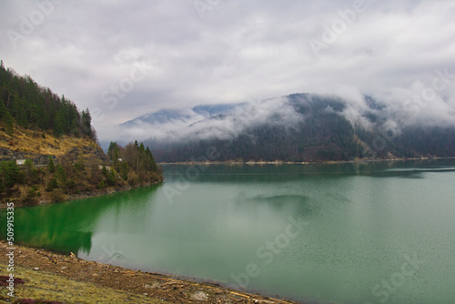 Grüner See in den Bergen mit Nebel 